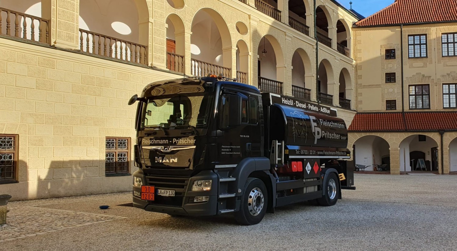 Weißer Tankzug bei Nacht vor einer Autobahnauffahrt